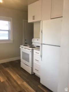 Kitchen with white appliances, dark wood-type flooring, white cabinets, and light countertops