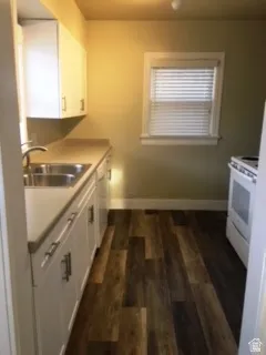 Kitchen featuring white cabinetry, white stove, dark wood finished floors, and light countertops