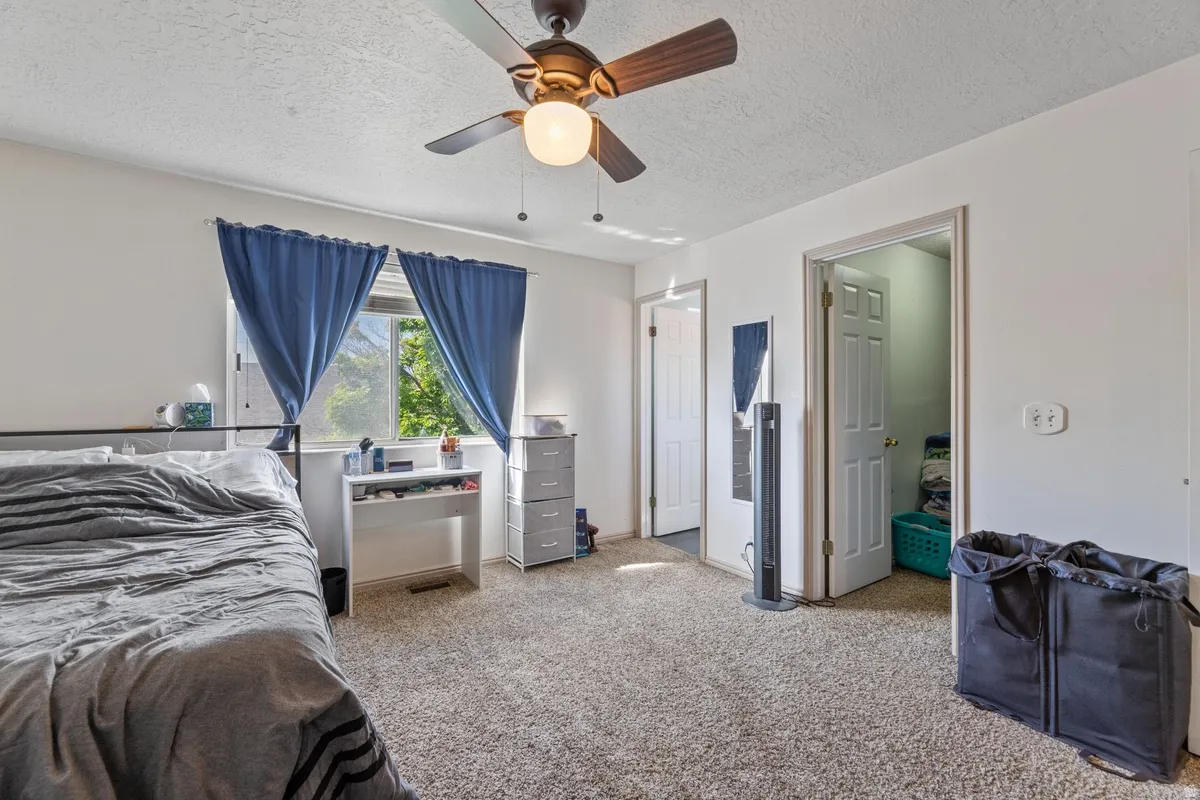 Bedroom with light colored carpet, a textured ceiling, and a ceiling fan
