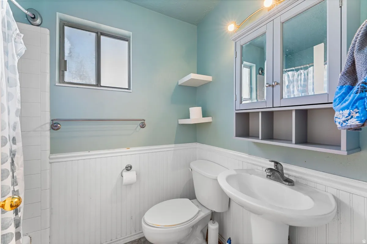 Full bath with a wainscoted wall and a shower with shower curtain