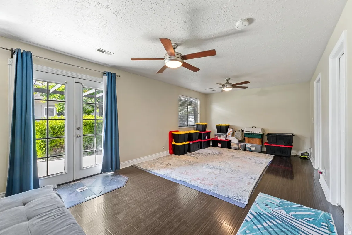 Game room with french doors, dark wood finished floors, a textured ceiling, and a ceiling fan