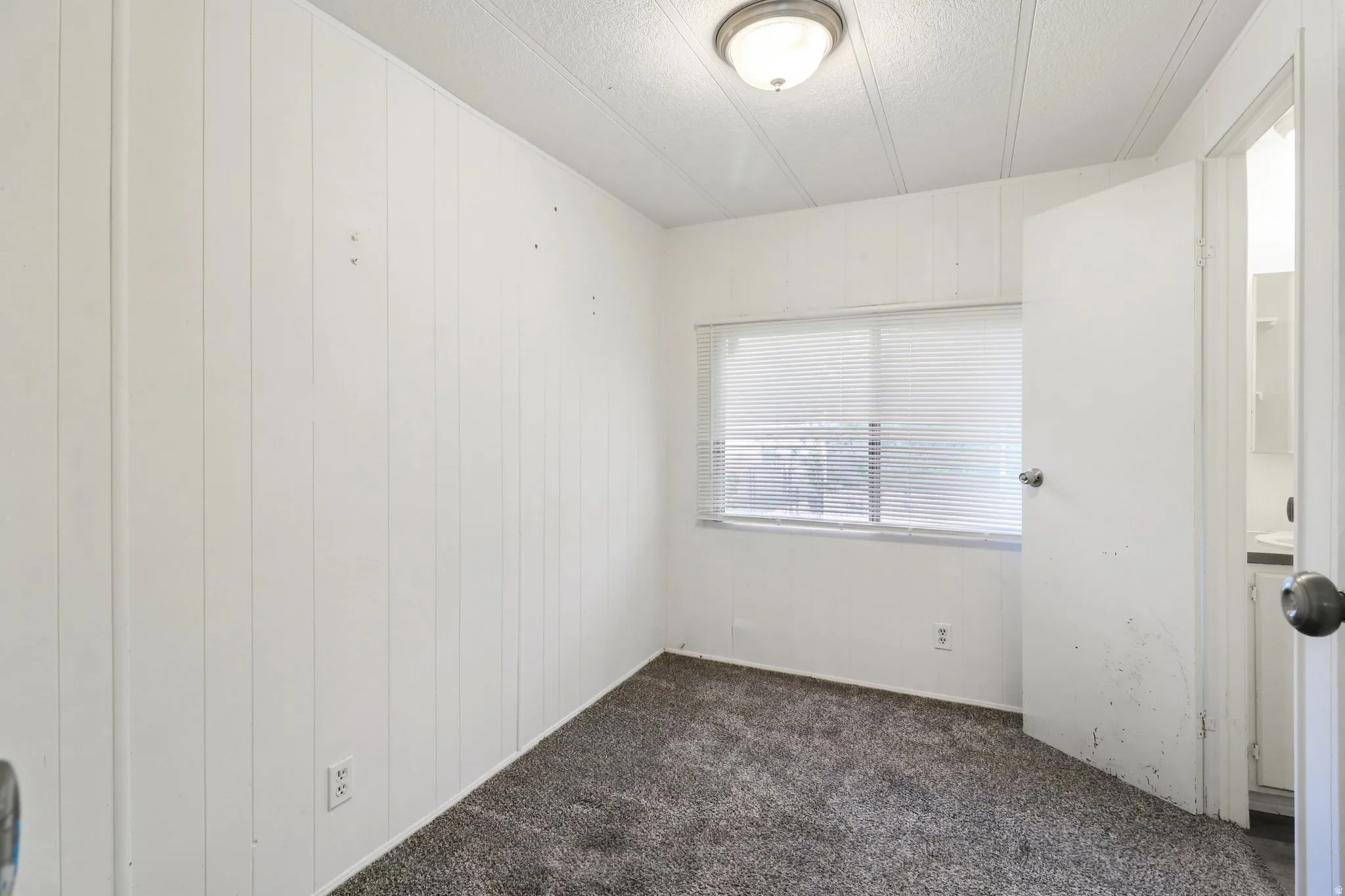 Spare room with dark colored carpet and a textured ceiling
