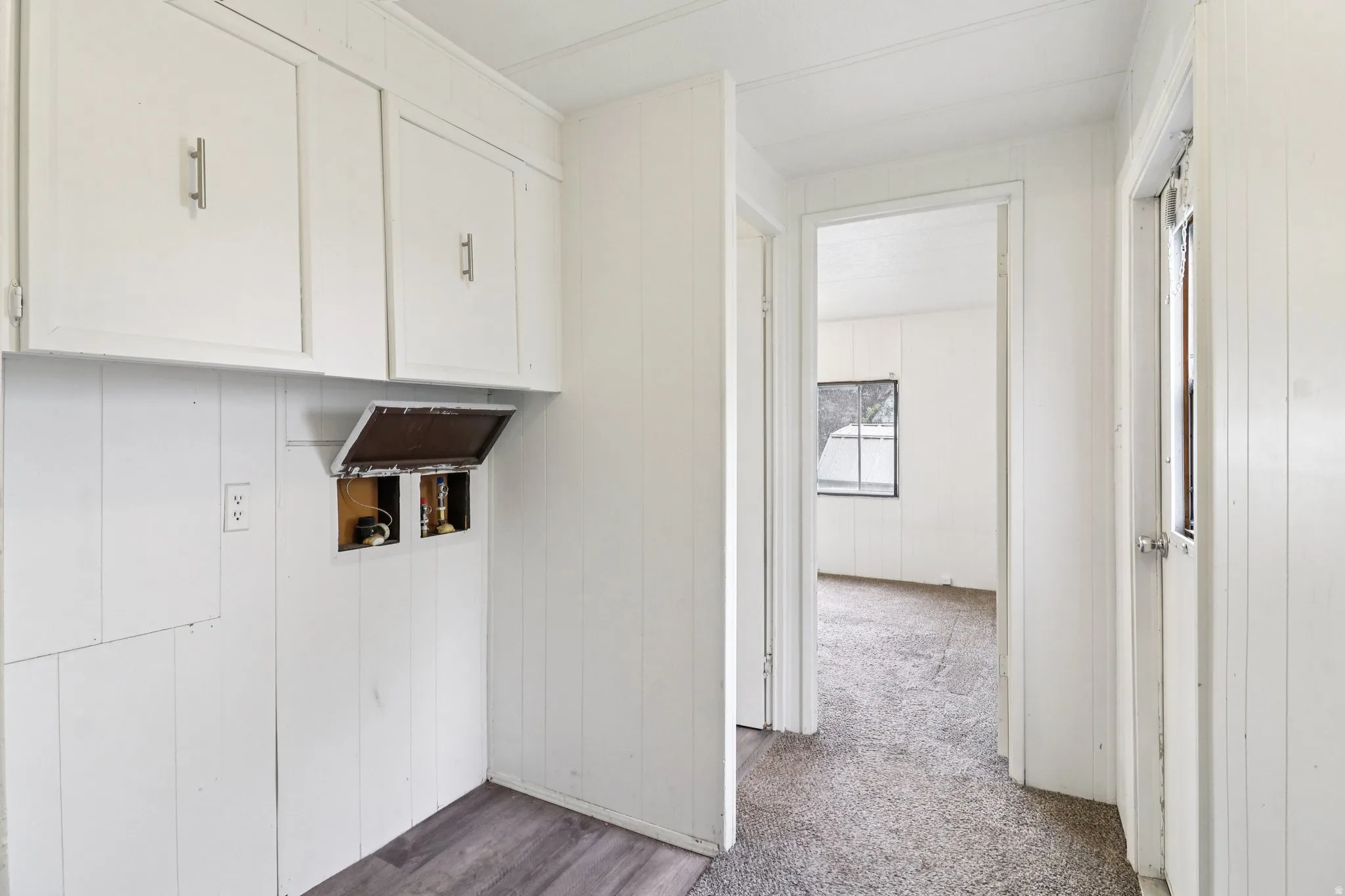 Laundry area with washer hookup, cabinet space, wooden walls, dark carpet, and dark wood-style floors