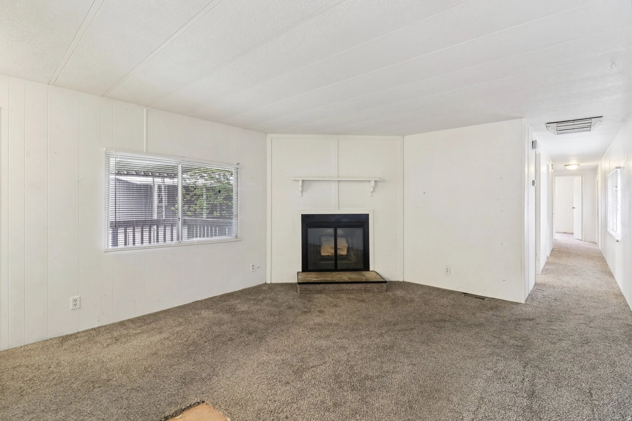 Unfurnished living room featuring carpet, a glass covered fireplace, and cooling unit