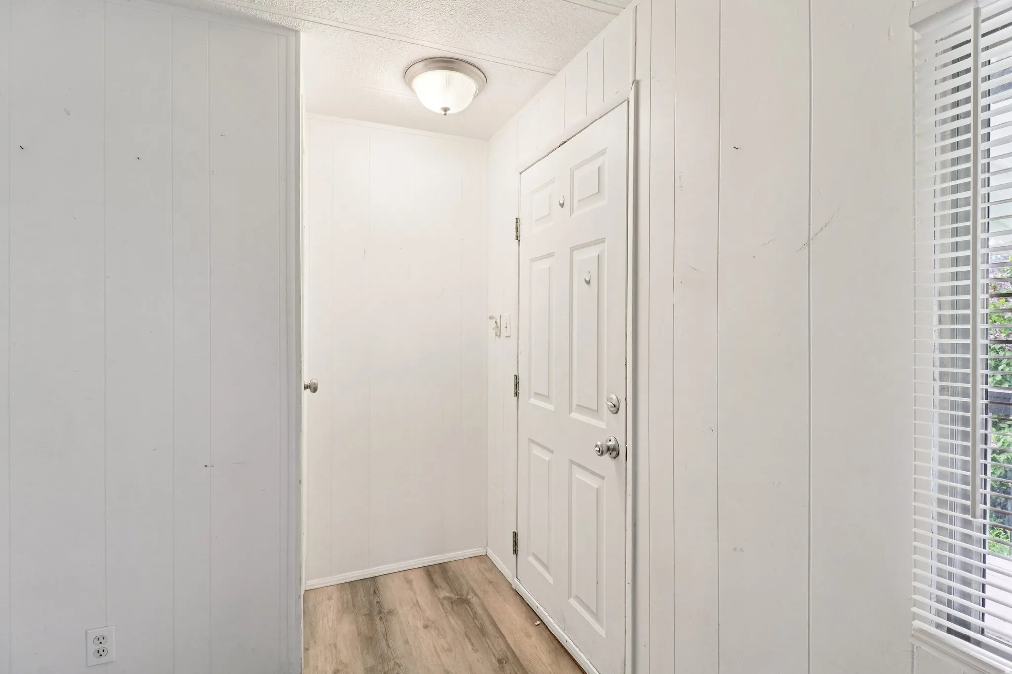 Hall featuring wood walls, light wood finished floors, and a textured ceiling