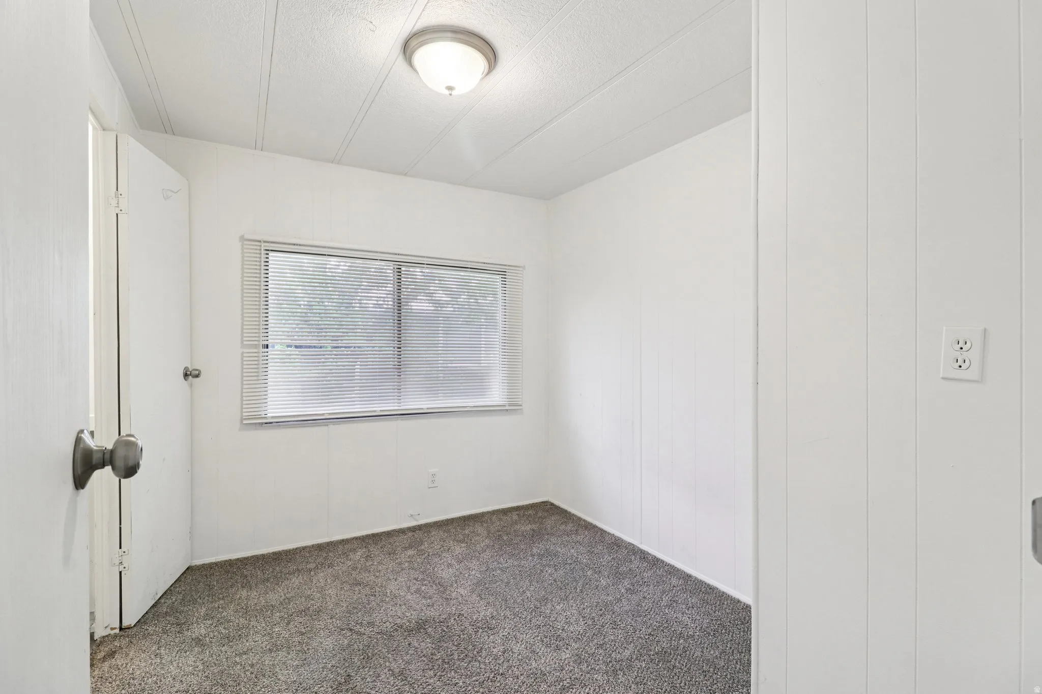 Unfurnished room featuring dark carpet and a textured ceiling