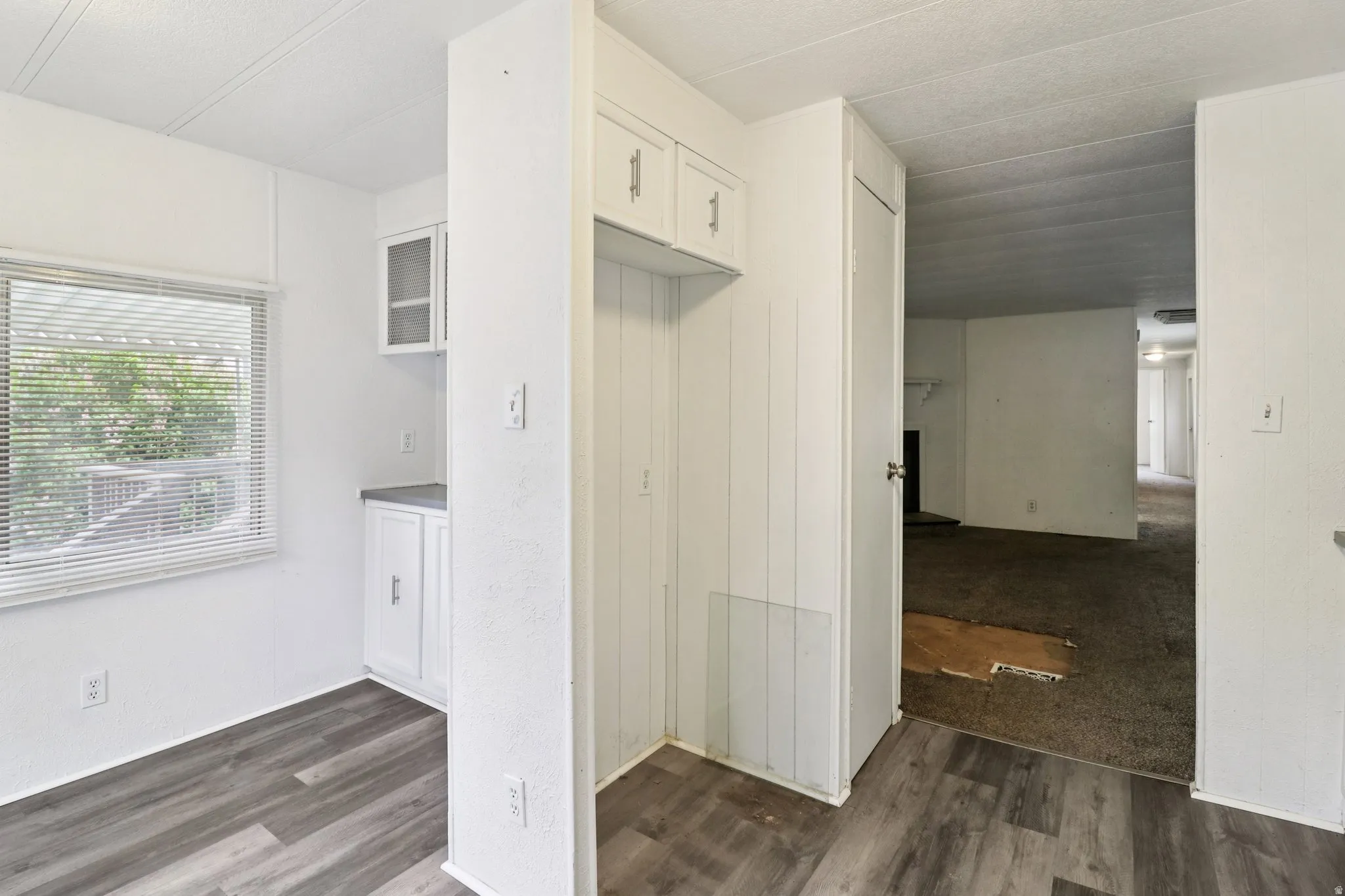 Kitchen with dark wood-style flooring and white cabinetry