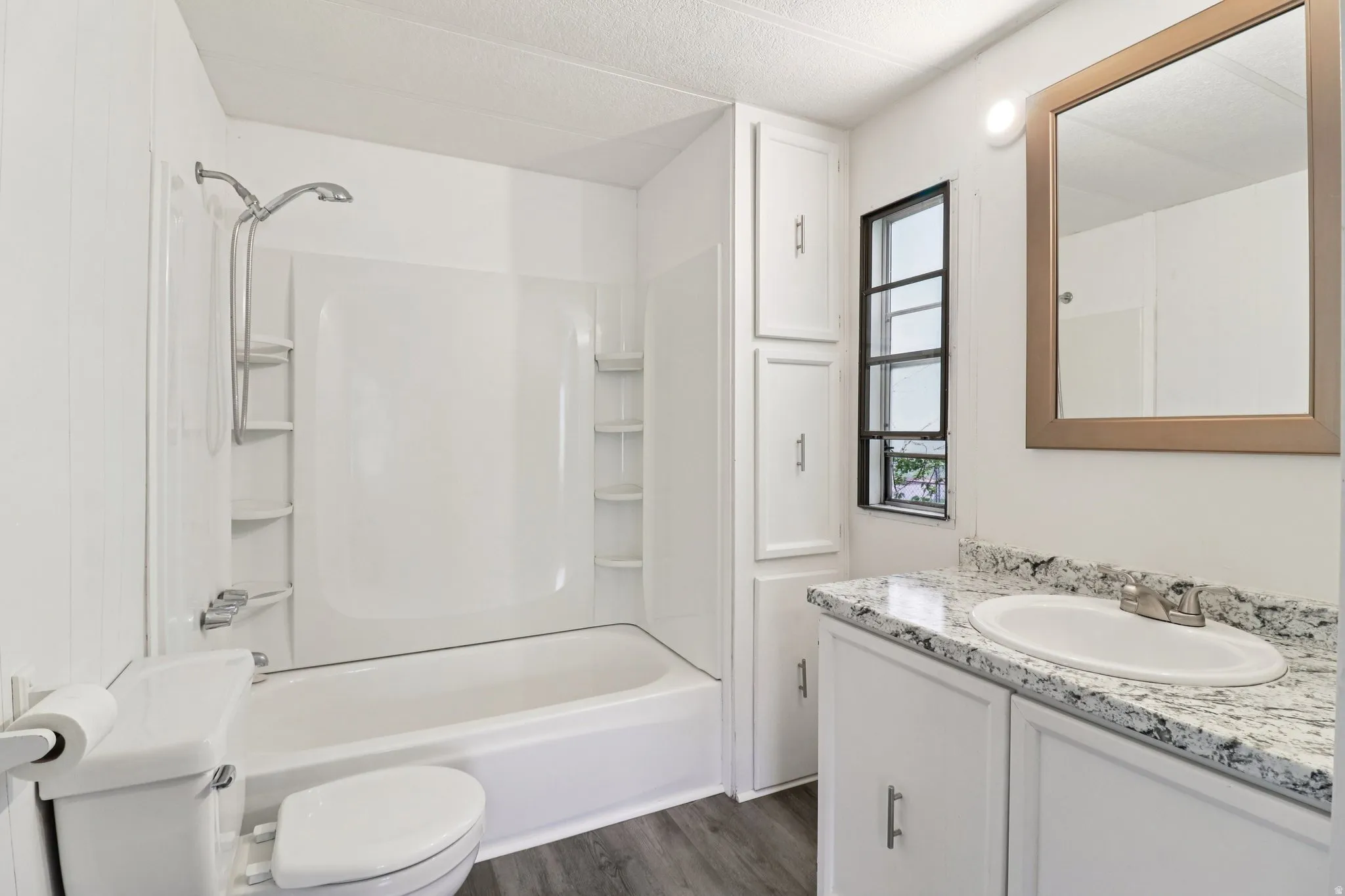 Bathroom featuring vanity, a textured ceiling, dark wood-style flooring, and shower / bath combination