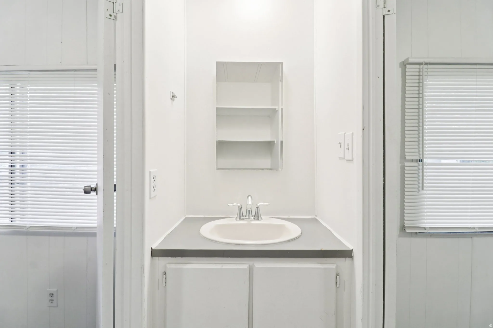 Bathroom with wood walls, vanity, wainscoting, and a decorative wall