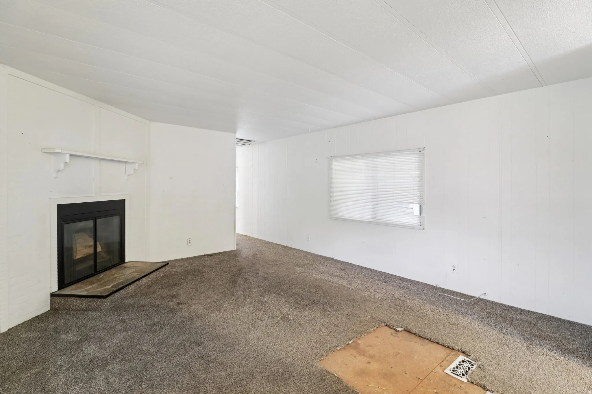 Unfurnished living room with carpet and a glass covered fireplace