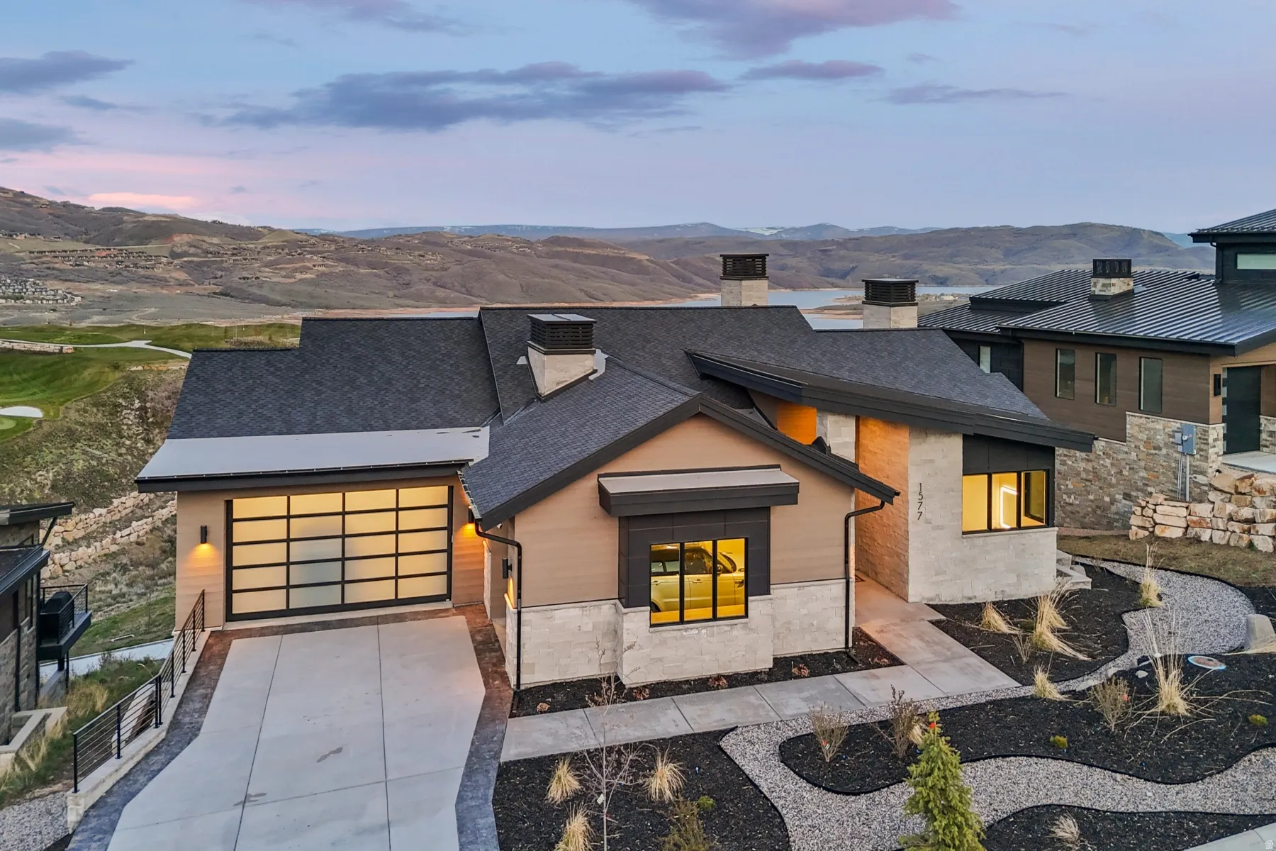 Modern home featuring a chimney, a mountain view, driveway, stone siding, and a garage