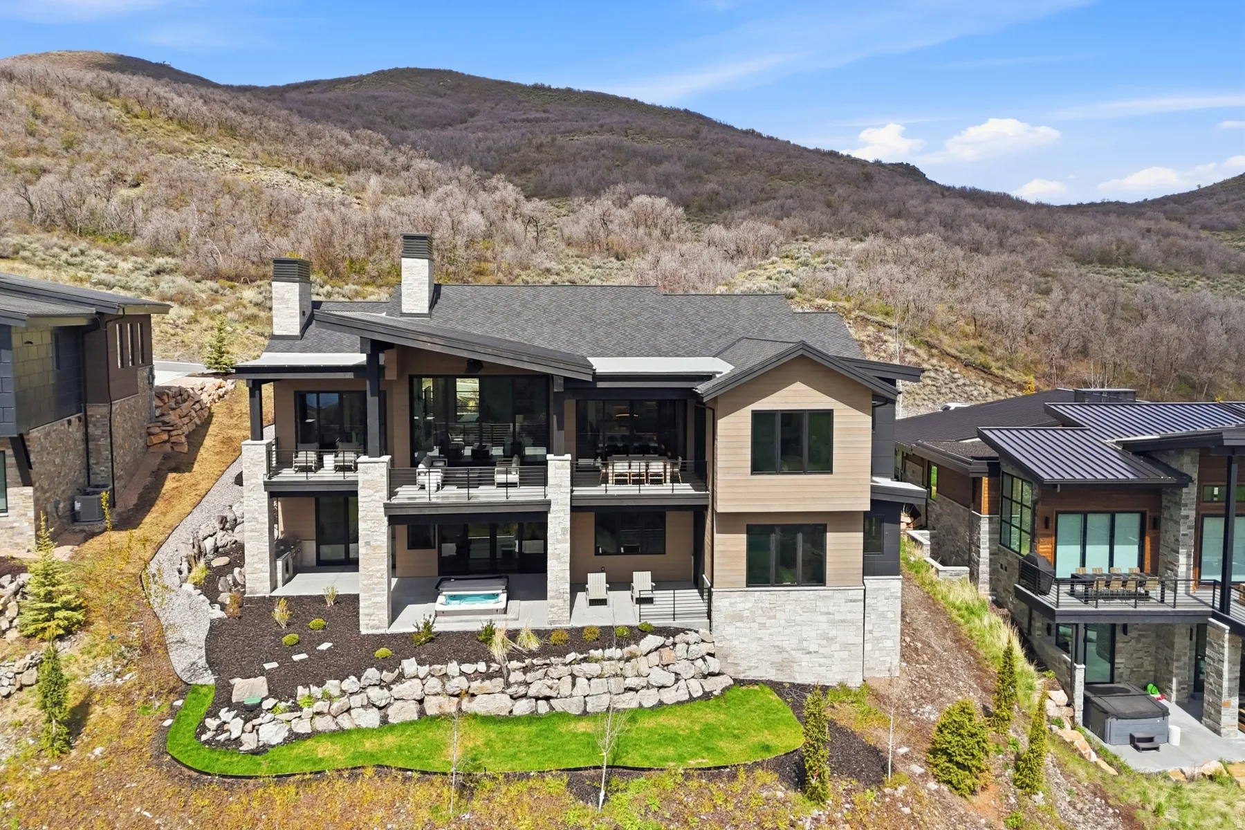 Back of property with stone siding, a mountain view, a chimney, and a patio area