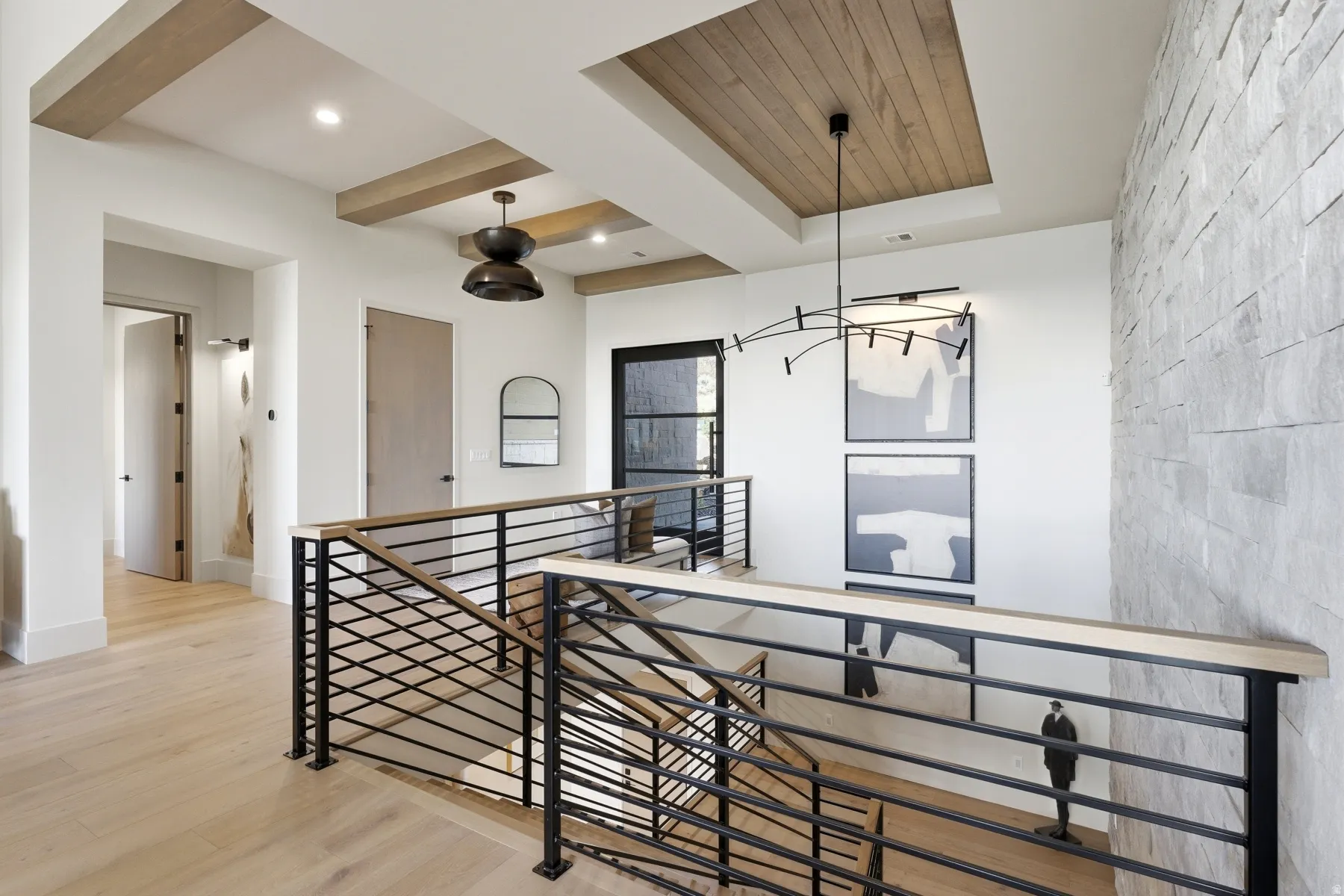 Corridor featuring light wood-style floors, an upstairs landing, beam ceiling, and a chandelier