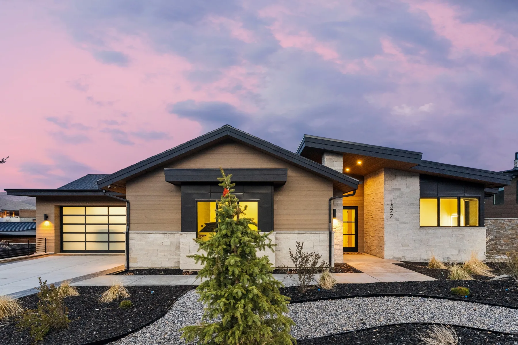 Contemporary house with stone siding, a garage, and driveway