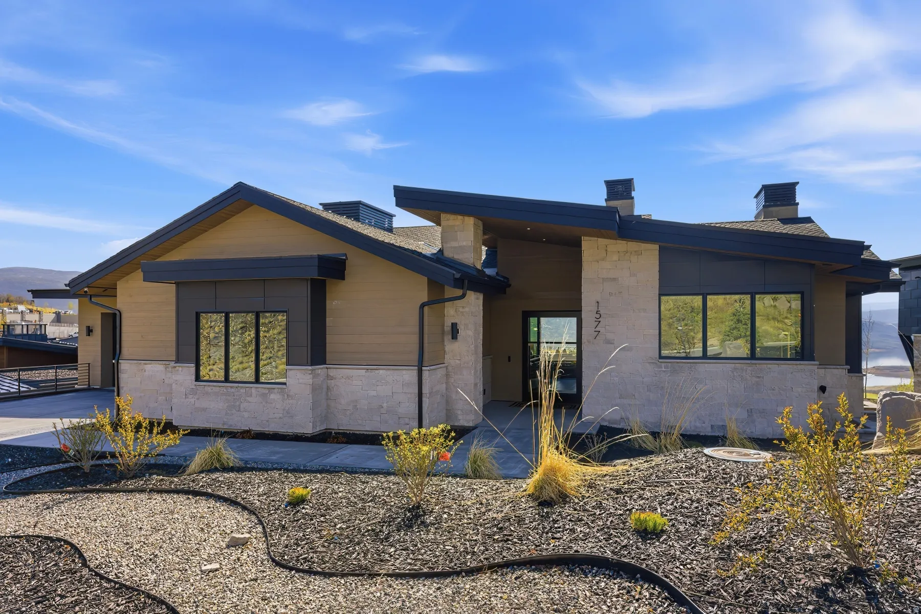 Contemporary house with a chimney, stone siding, and a garage