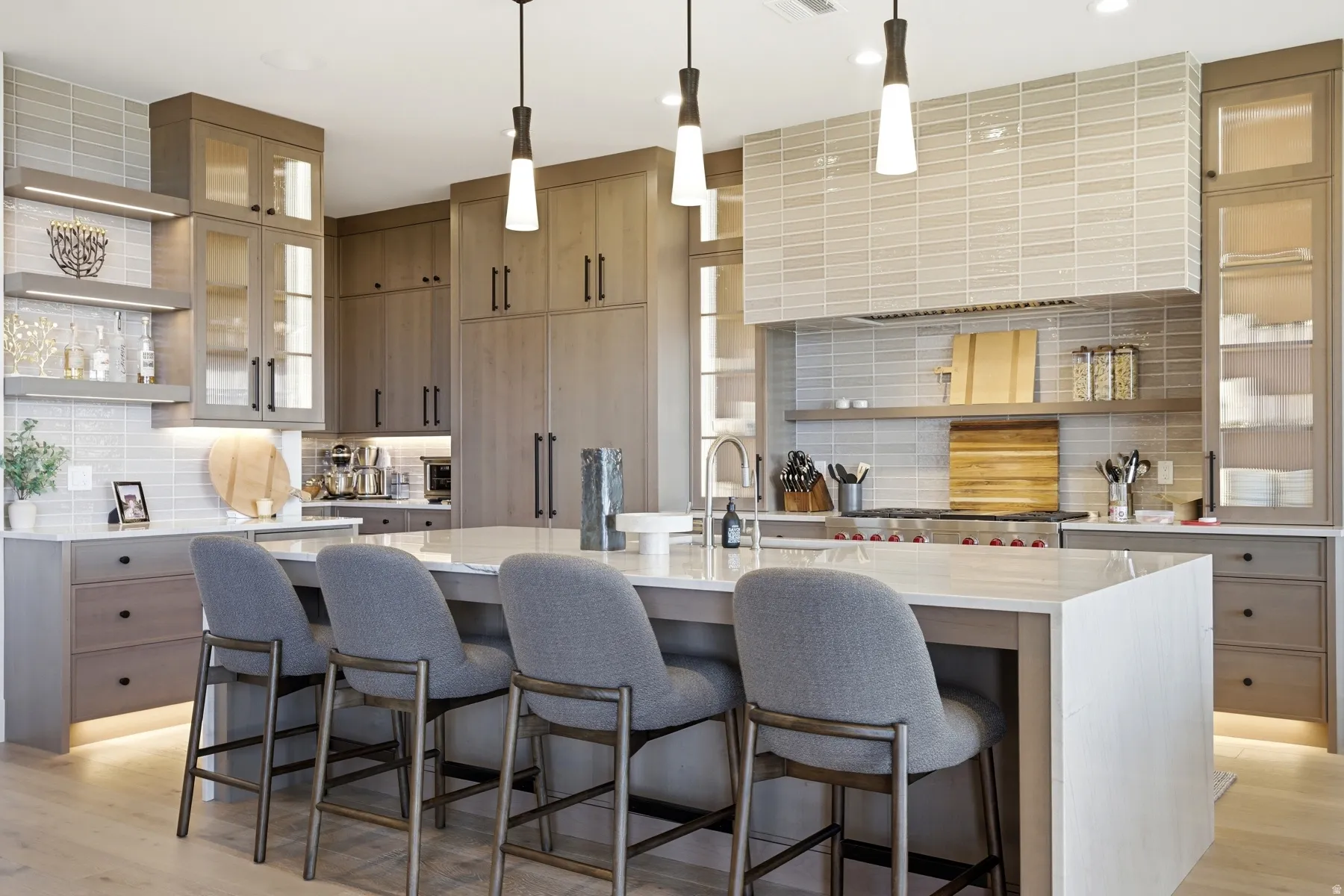 Kitchen with open shelves, glass insert cabinets, tasteful backsplash, a kitchen island with sink, and light stone countertops
