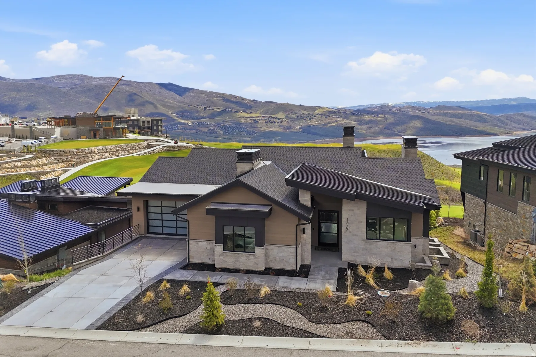 Modern home featuring a chimney, a mountain view, driveway, stone siding, and an attached garage