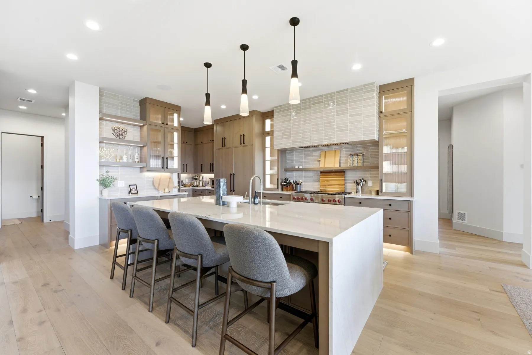 Kitchen with open shelves, a kitchen breakfast bar, backsplash, light stone counters, and a spacious island