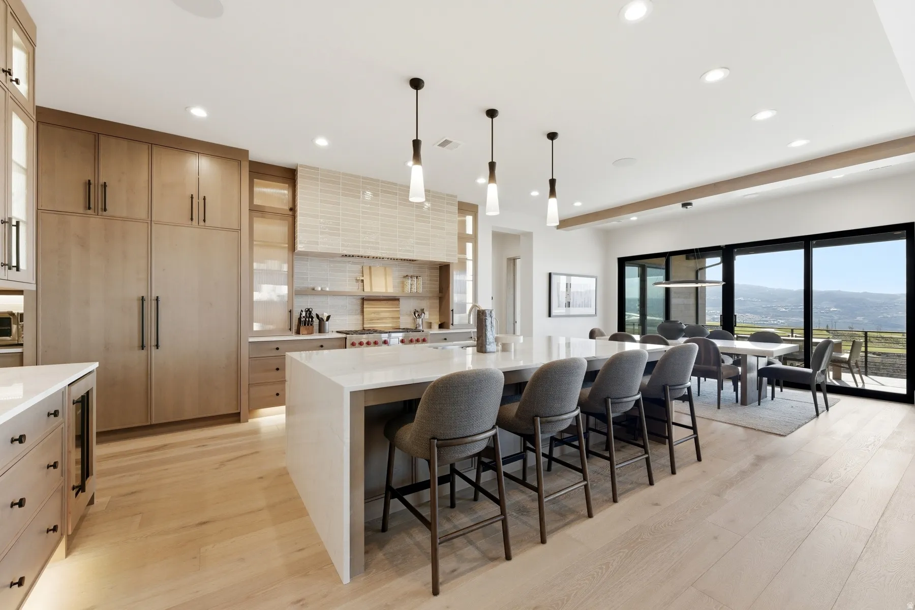 Kitchen featuring light wood finish cabinets, a breakfast bar, a large island with sink, light stone countertops, and light wood-type flooring