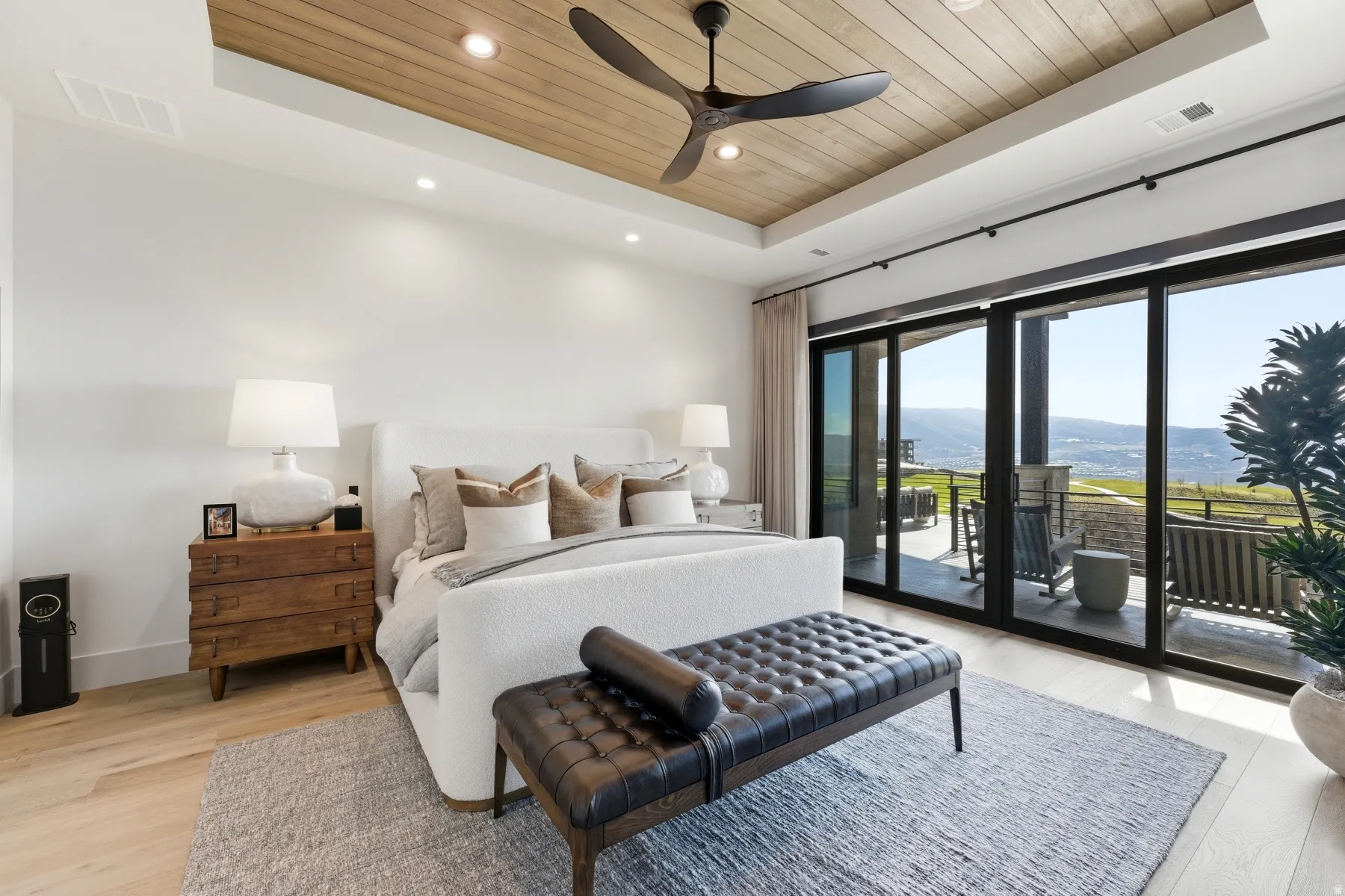 Bedroom featuring a wooden tray ceiling, access to outside, light wood-type flooring, a ceiling fan, and a mountain view