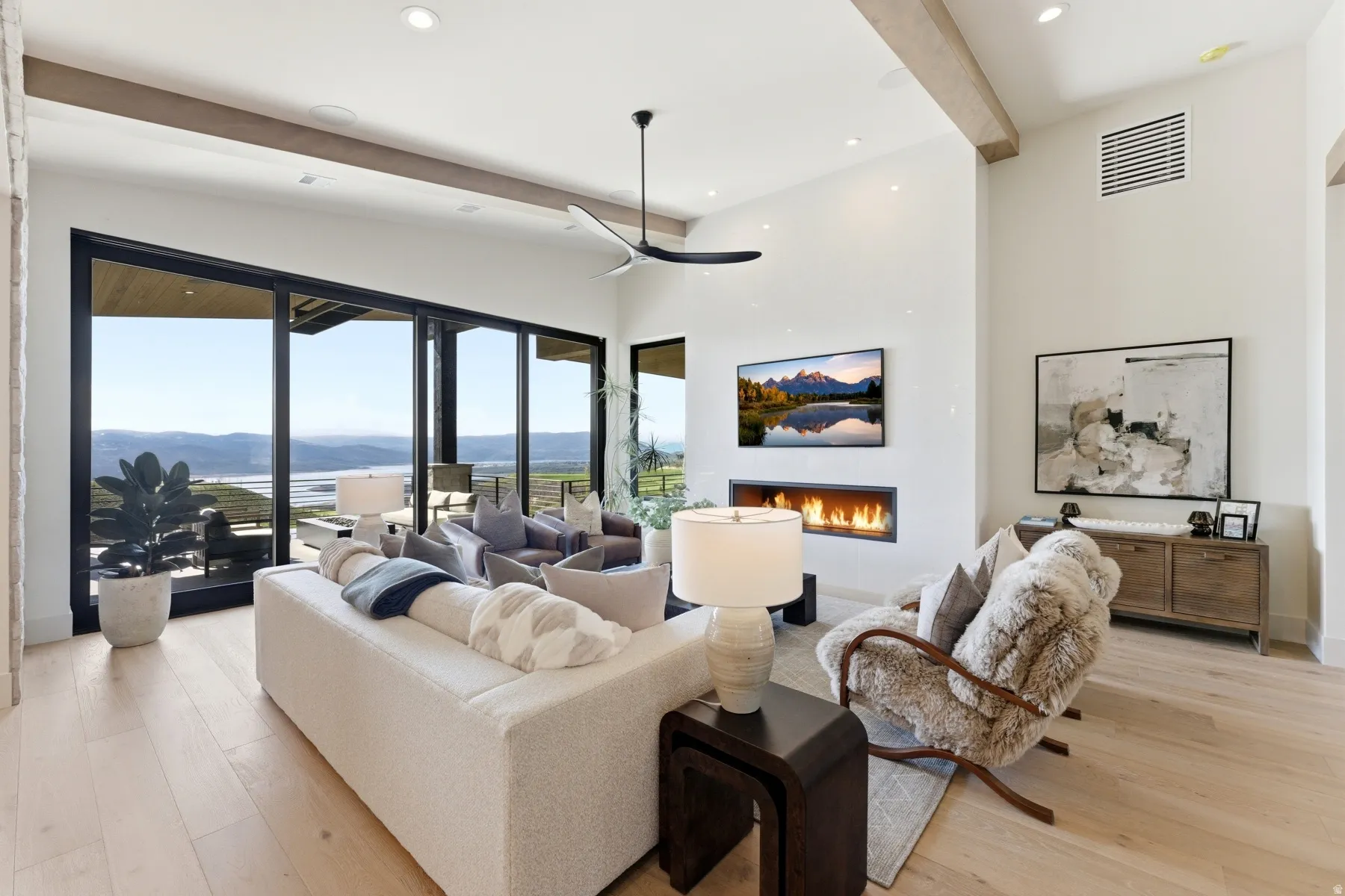 Living room featuring light wood-type flooring, a warm lit fireplace, recessed lighting, and ceiling fan