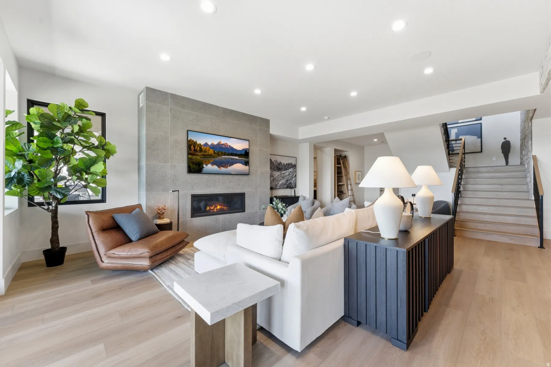 Living area featuring light wood-type flooring, a tiled fireplace, and recessed lighting
