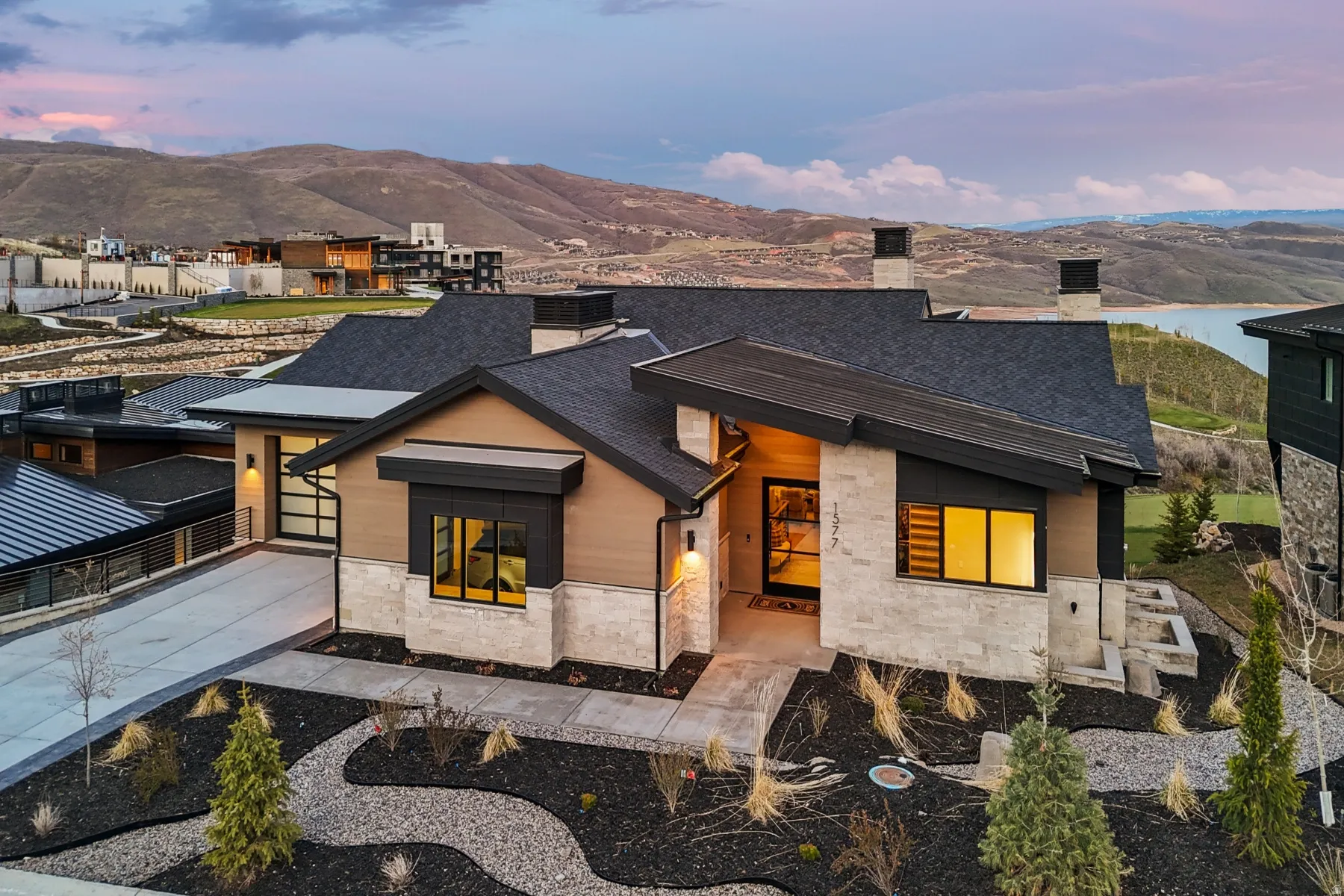 Contemporary house with stone siding, concrete driveway, a chimney, a mountain view, and a garage