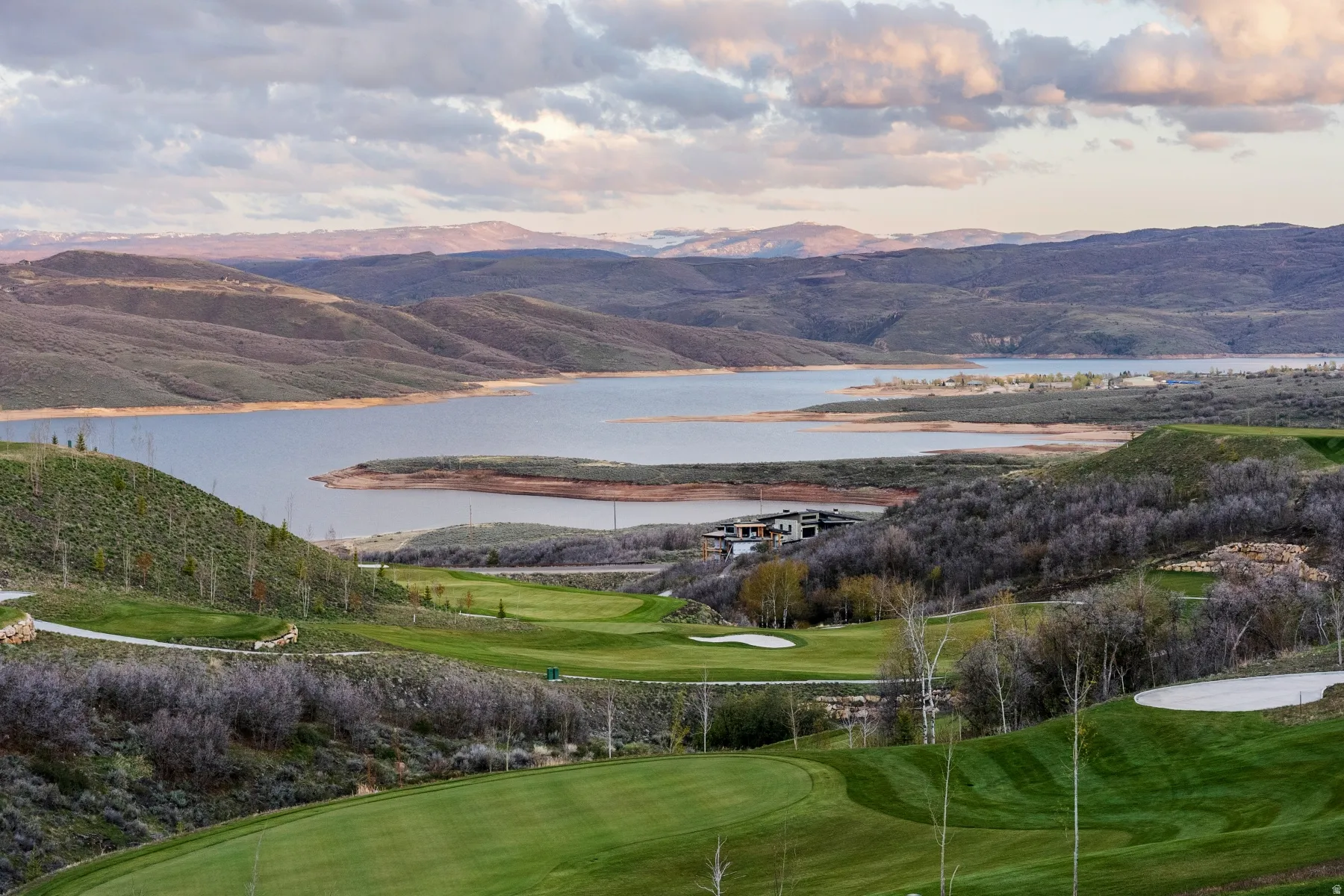 View of mountain backdrop with a nearby body of water and a golf course