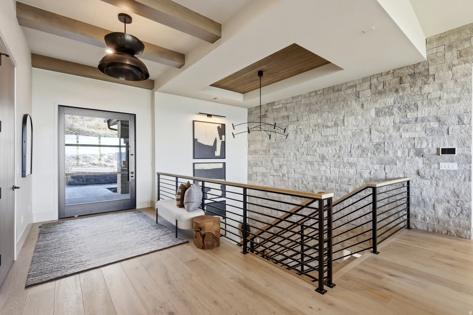 Foyer entrance with light wood-style flooring, beamed ceiling, an accent wall, and a tray ceiling