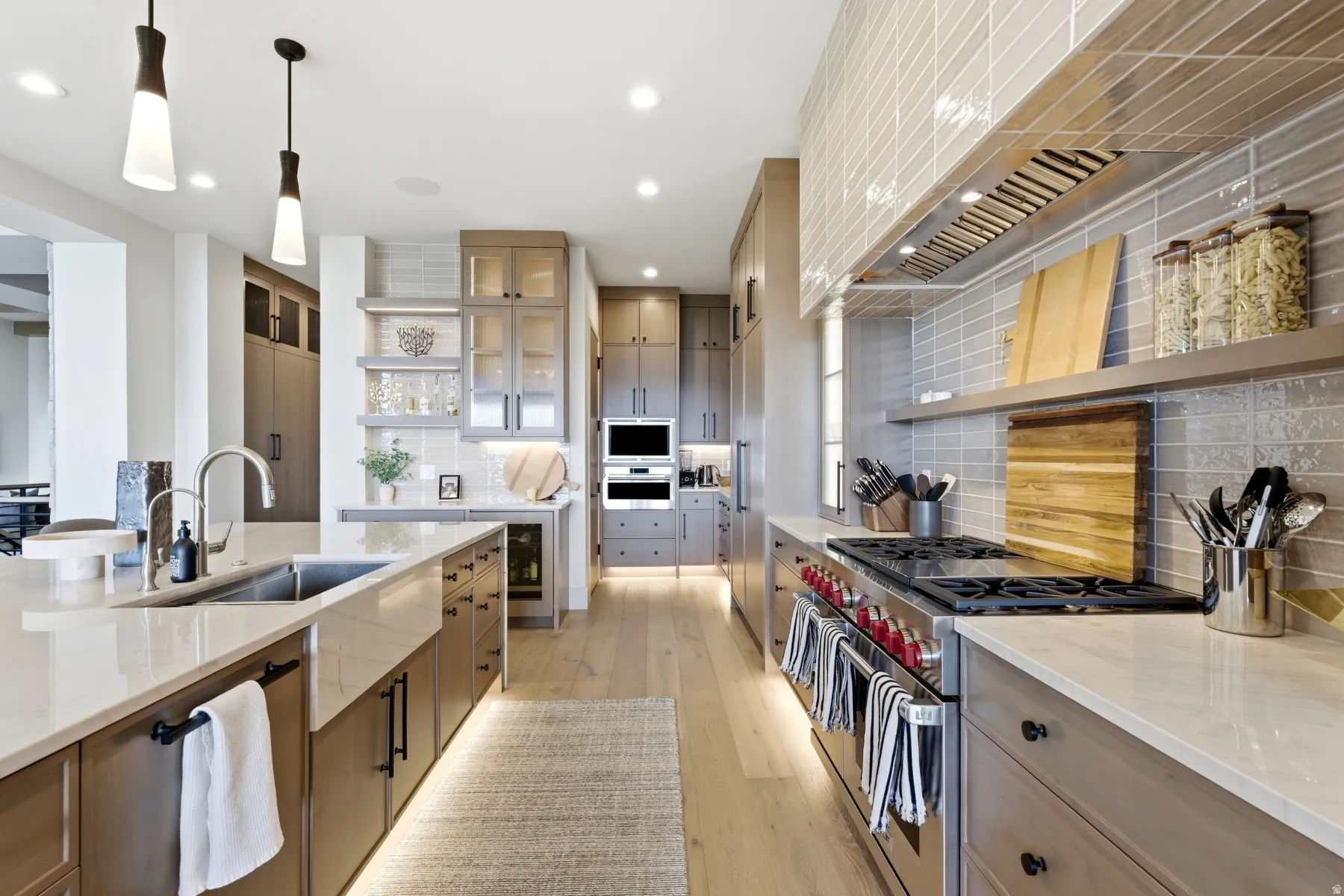 Dual tone kitchen featuring open shelves, stainless steel appliances, pendant lighting, light stone counters, and light wood-style flooring