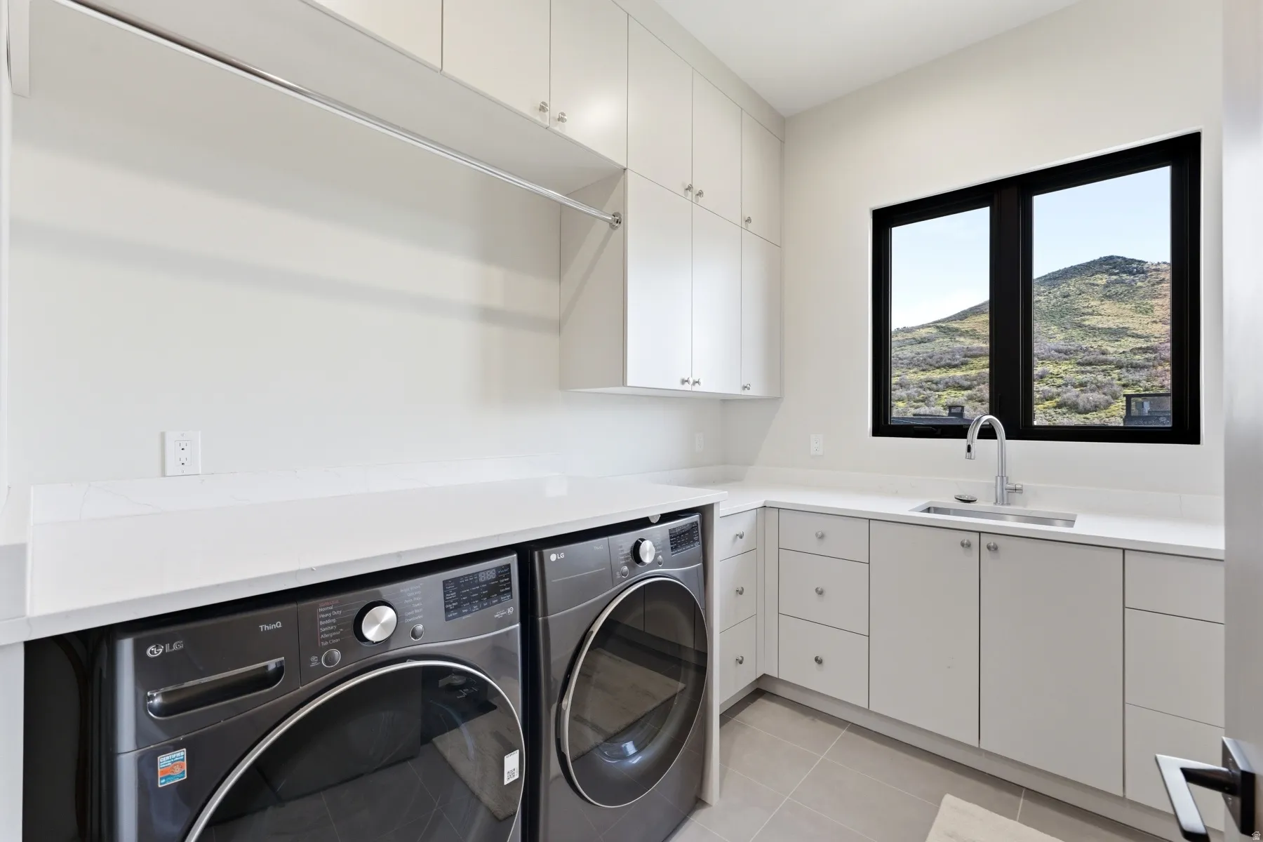Laundry room featuring cabinet space, light tile patterned floors, and washing machine and dryer