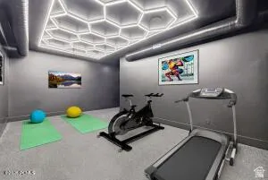 Recreational space featuring a hexagon-patterned ceiling light fixture, exposed ceiling ductwork, and gray-toned walls
