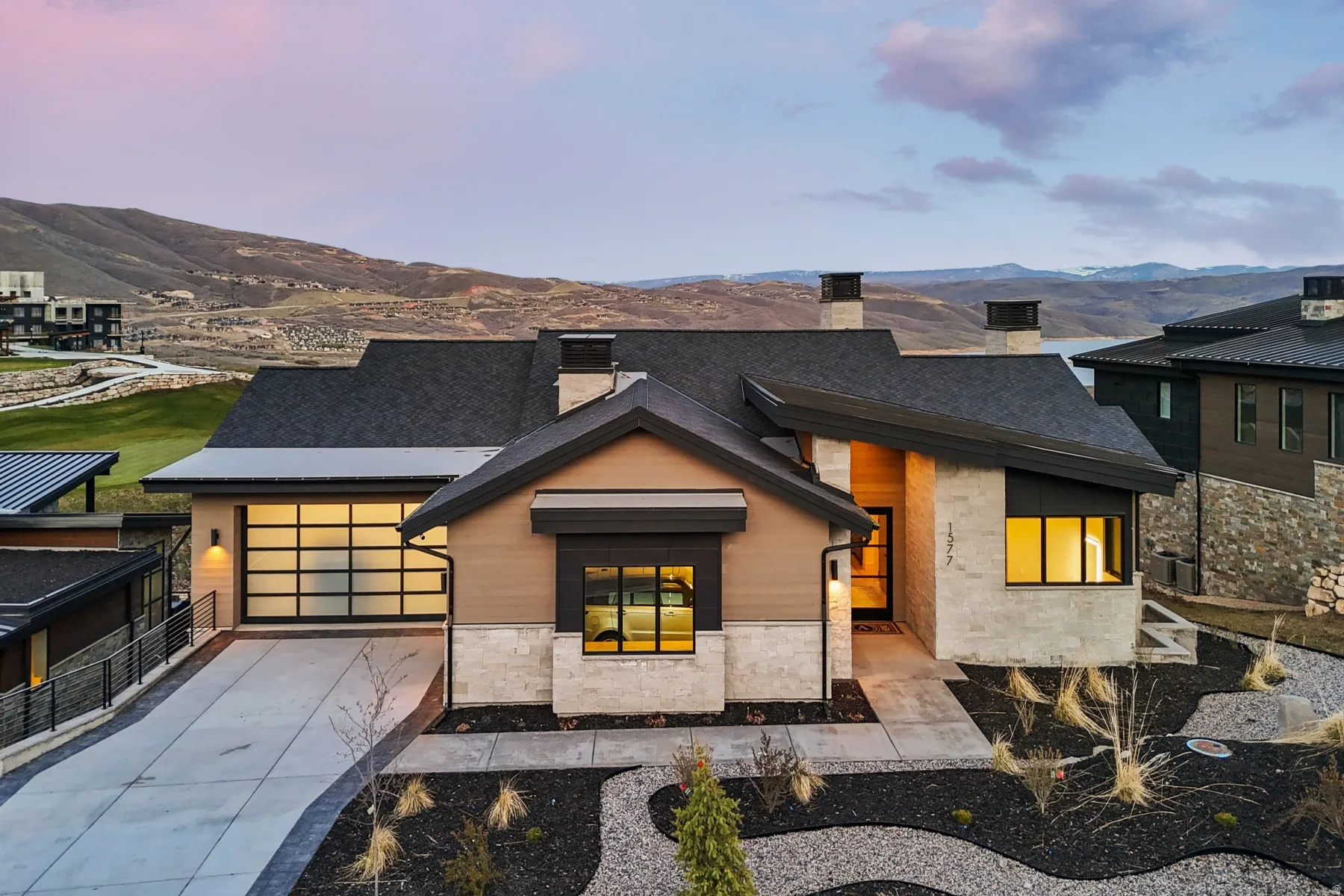 View of front of property with stone siding, a chimney, concrete driveway, a garage, and a mountain view