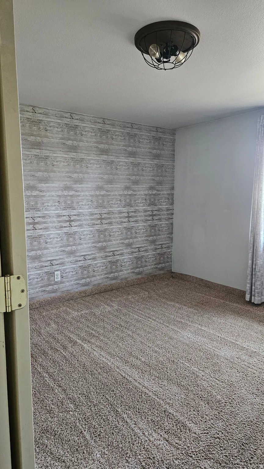 Carpeted empty room featuring wood walls