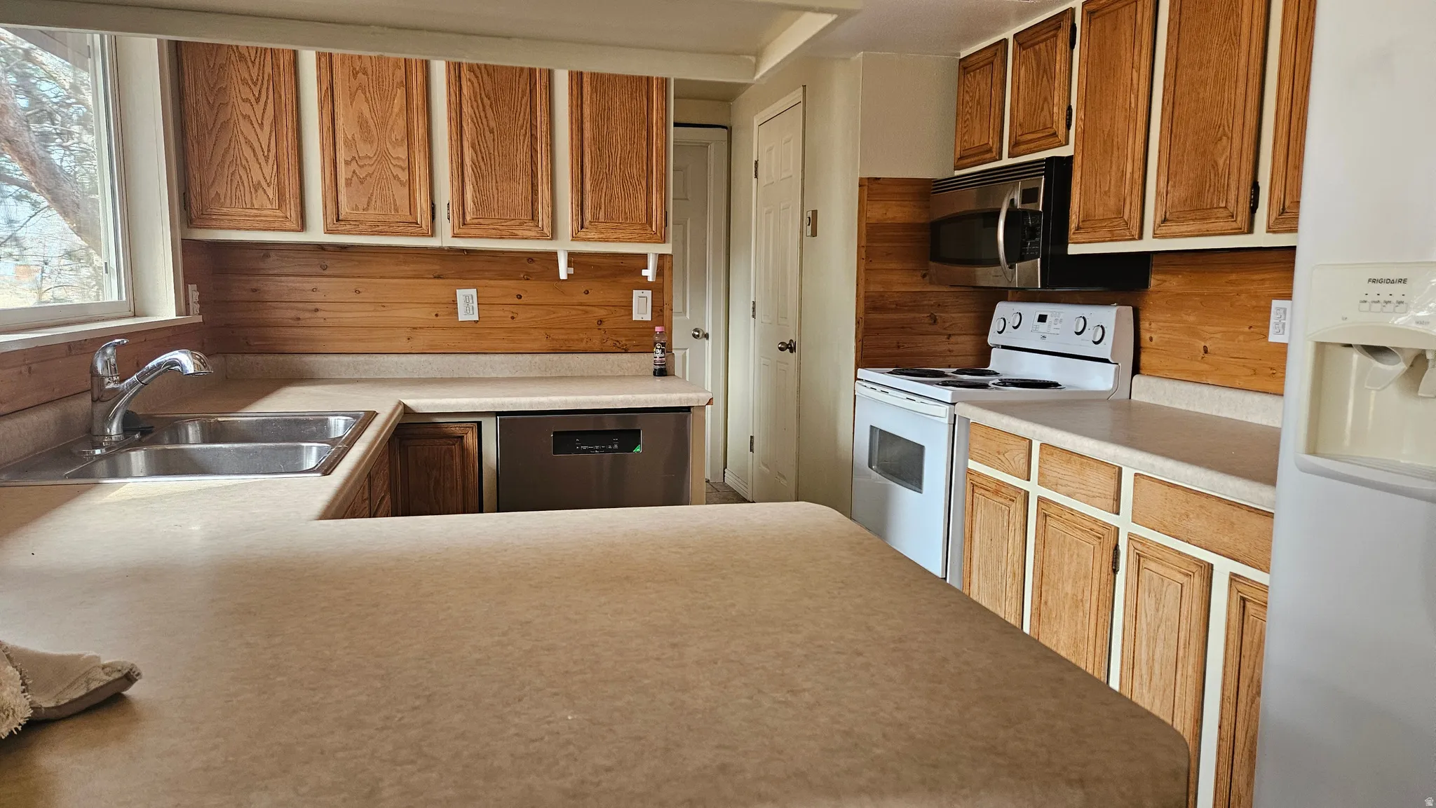 Kitchen featuring white appliances, light countertops, and wood finish cabinets