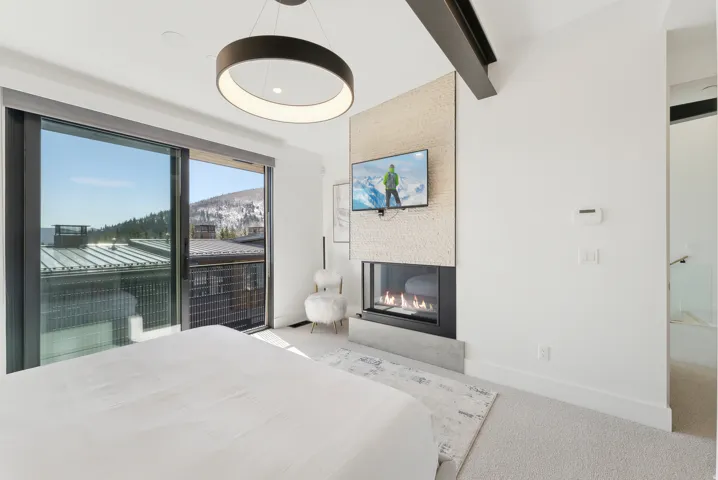 Bedroom featuring beamed ceiling, light carpet, and a multi sided fireplace