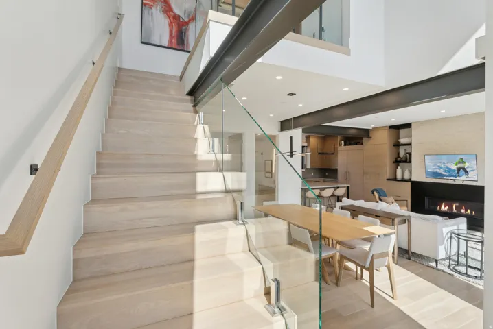 Stairs with a fireplace, recessed lighting, wood finished floors, and a high ceiling