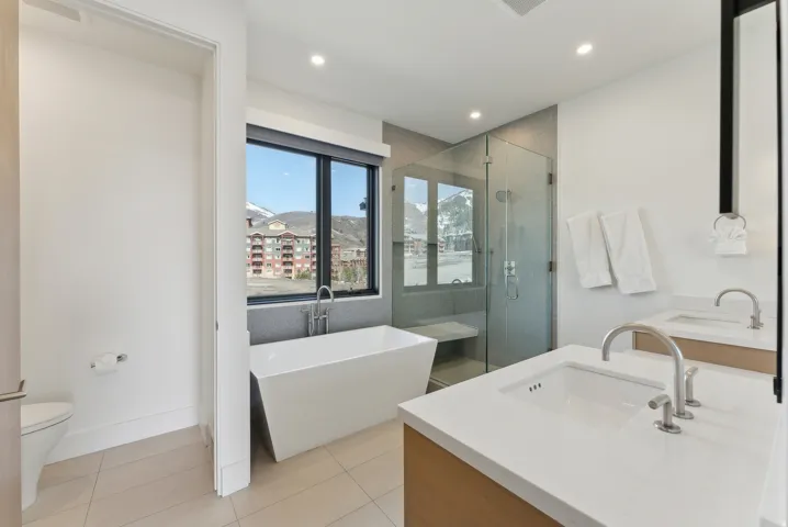 Bathroom featuring double vanity, a shower stall, a freestanding tub, light tile patterned flooring, and recessed lighting