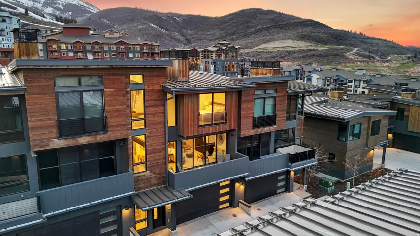 View of front of home with a mountain view, a garage, a metal roof, a residential view, and driveway
