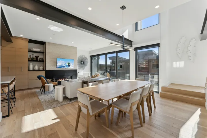 Dining space with light wood-type flooring, a ceiling fan, healthy amount of natural light, recessed lighting, and a high ceiling