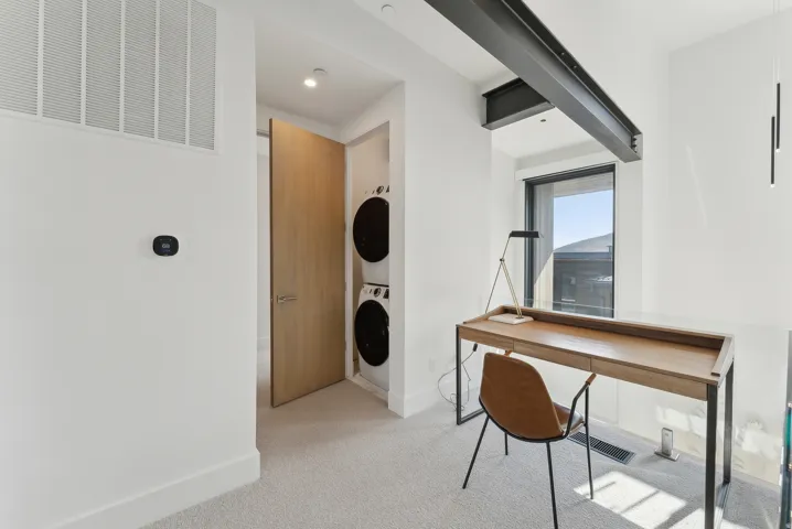 Office space featuring light colored carpet and stacked washer and clothes dryer