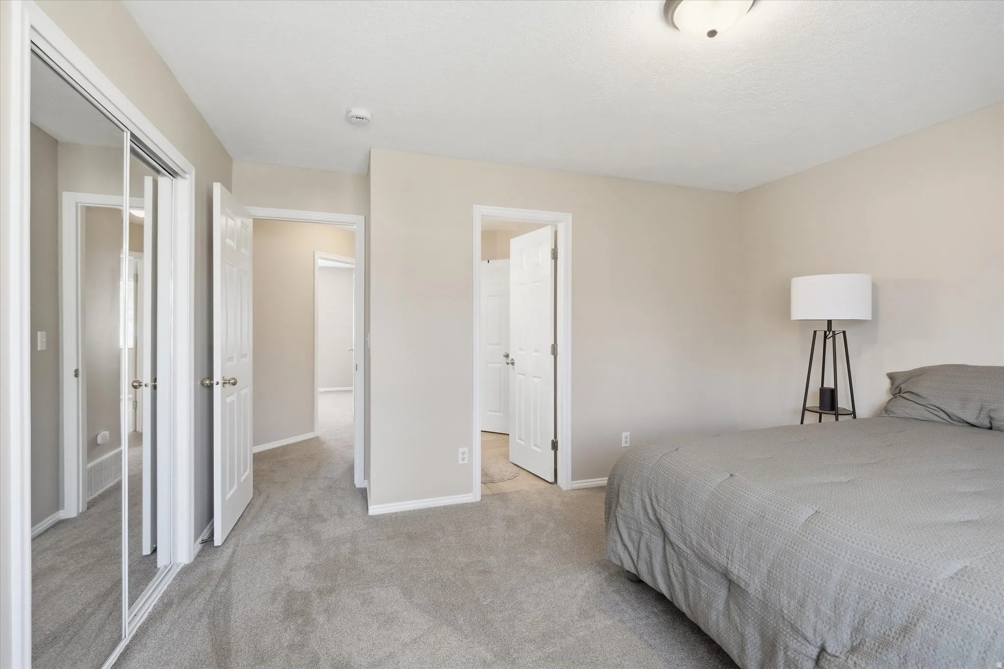 Neutral-toned bedroom featuring wall-to-wall carpeting, a semi-flush ceiling light fixture, and multiple doorways