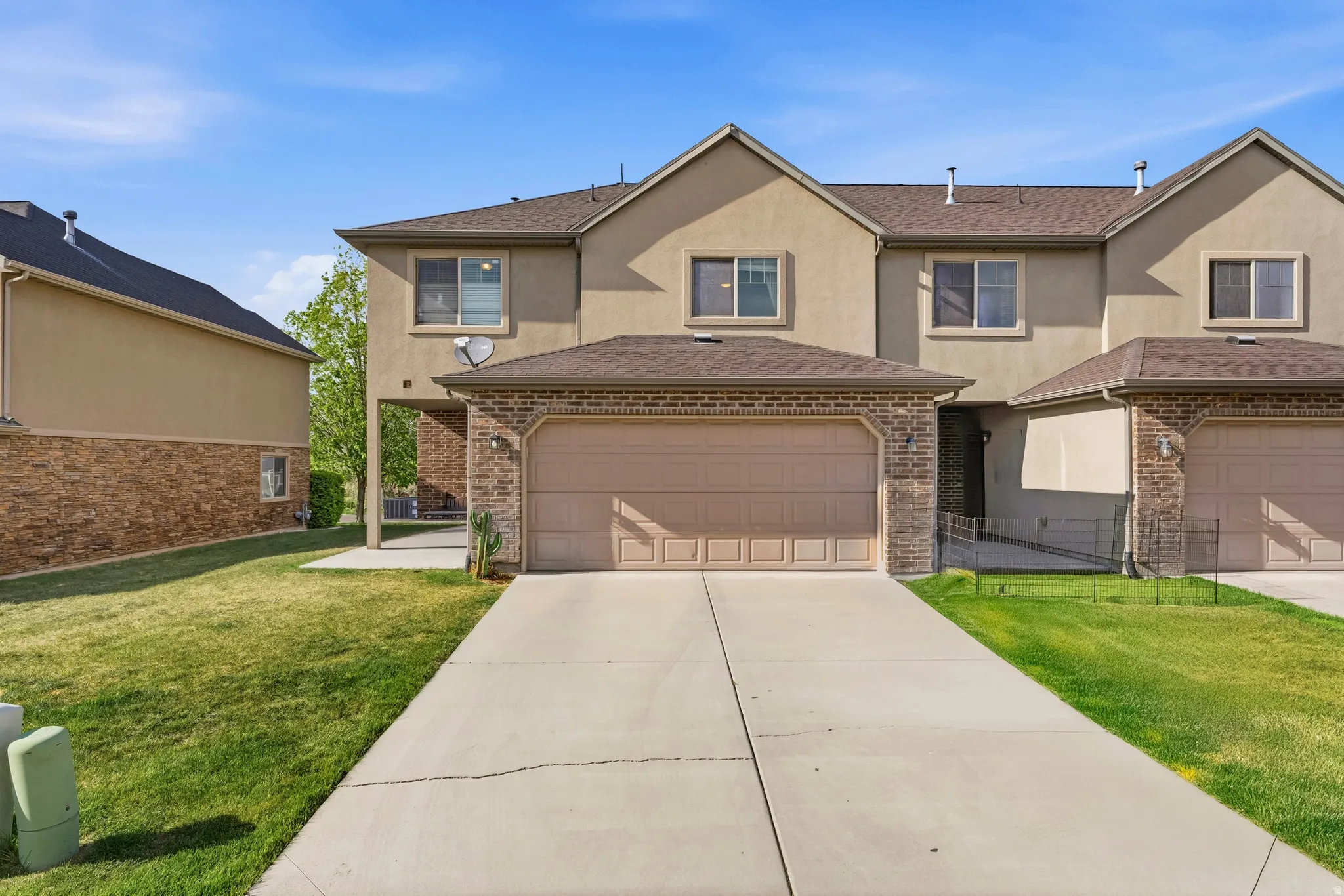Traditional home featuring stucco siding, a front yard, driveway, and brick siding