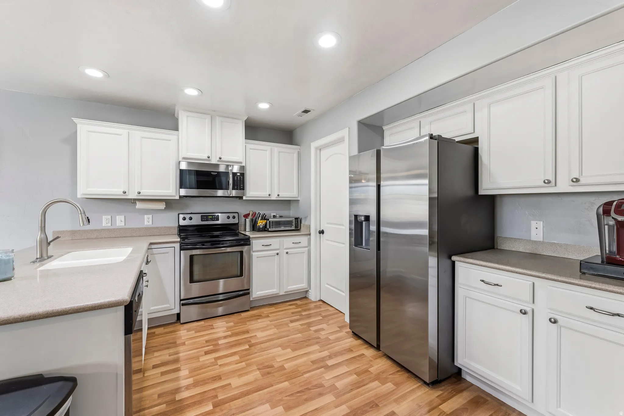 Kitchen featuring stainless steel appliances, white cabinetry, light wood-style floors, and recessed lighting