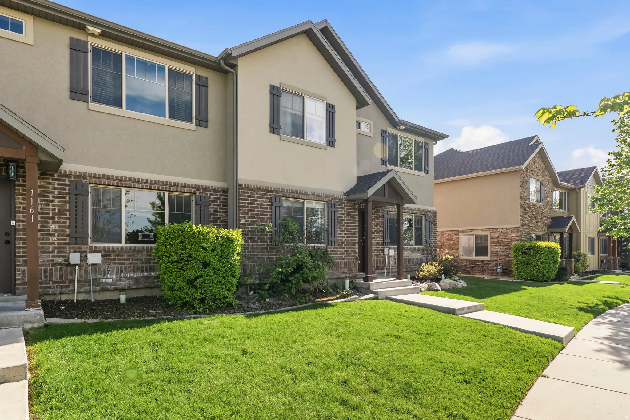 Traditional home featuring stucco siding, a front lawn, and brick siding