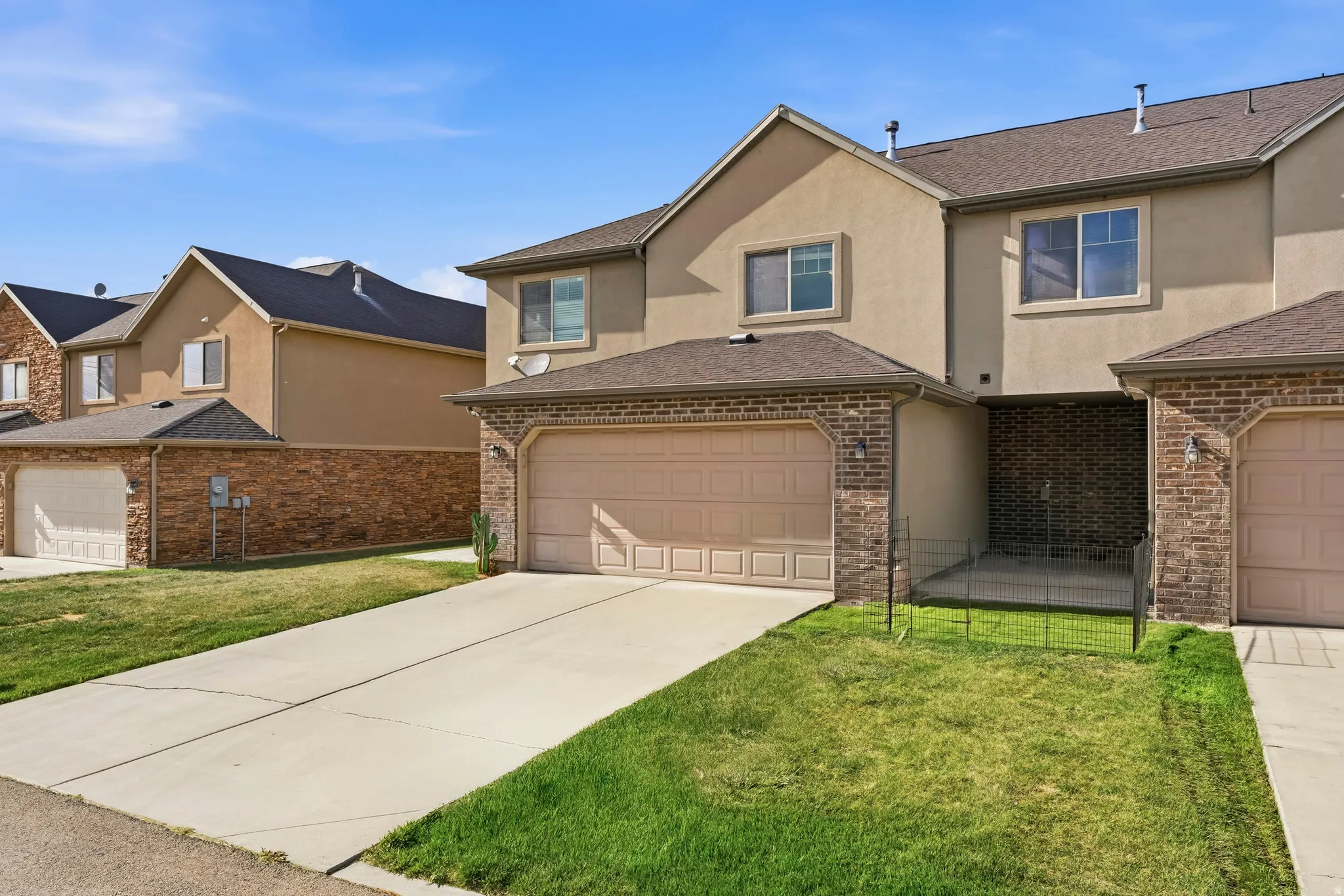 Traditional-style house with stucco siding, a front yard, concrete driveway, and brick siding