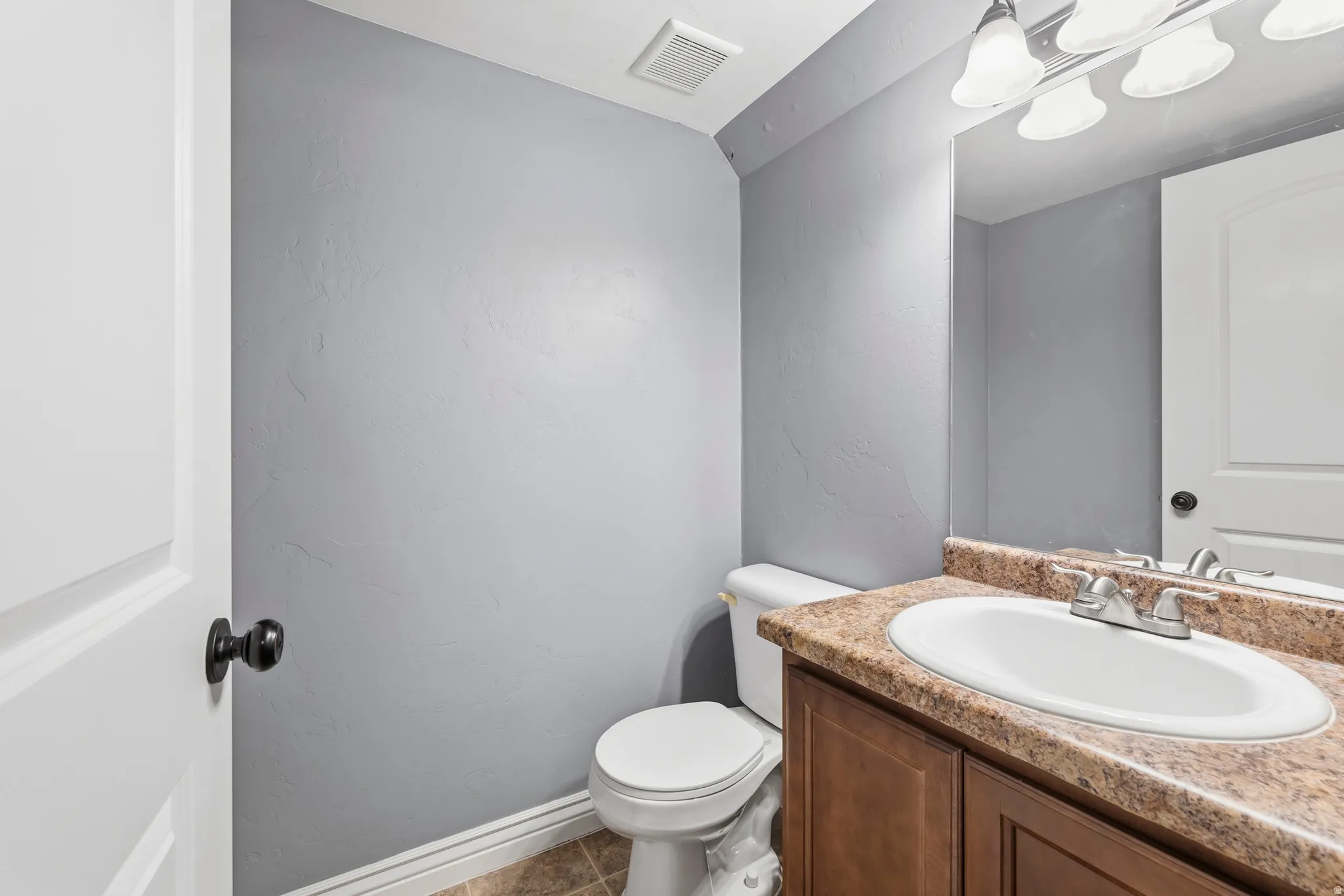 Bathroom with vanity and dark tile patterned flooring
