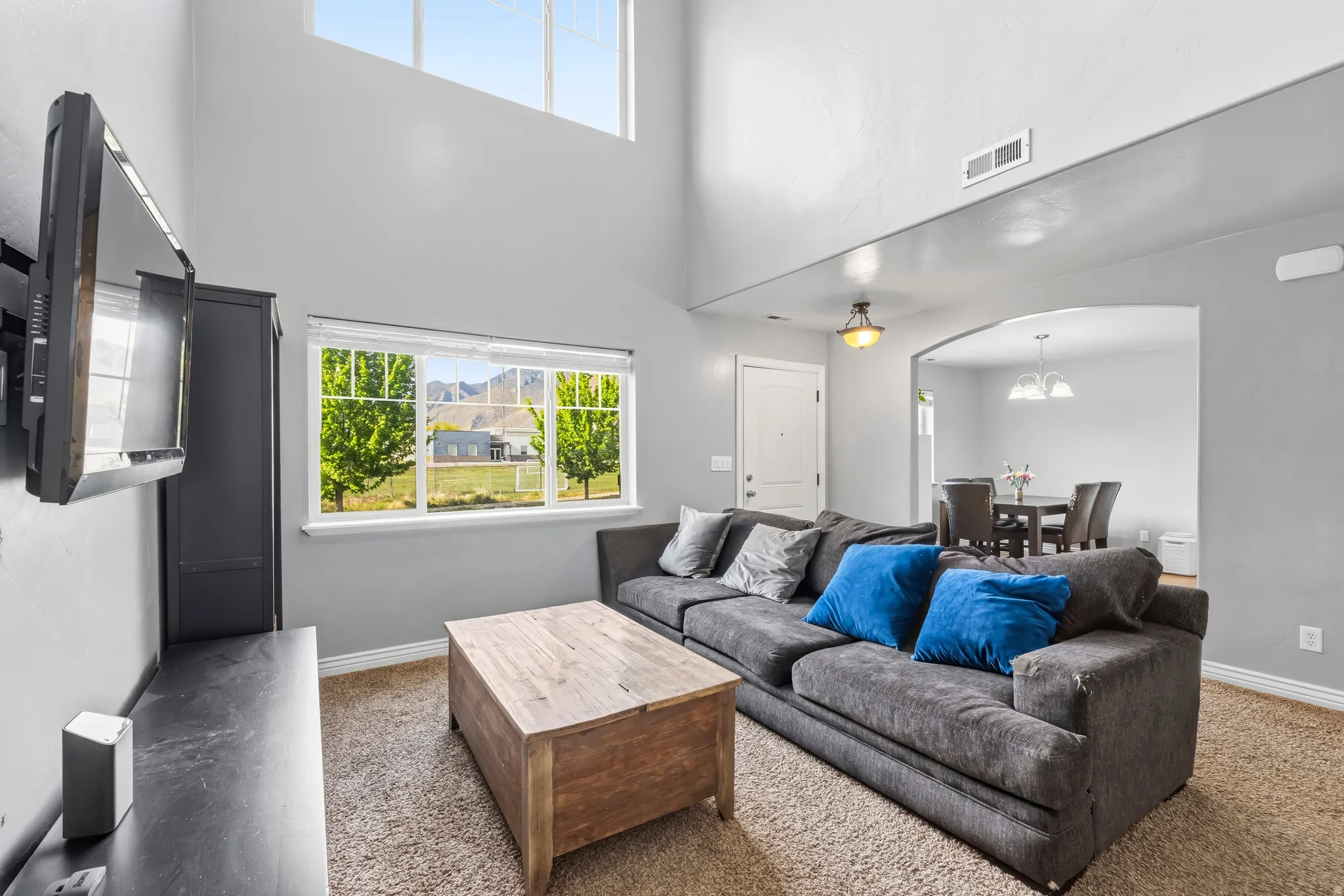 Carpeted living room with arched walkways, healthy amount of natural light, and a high ceiling