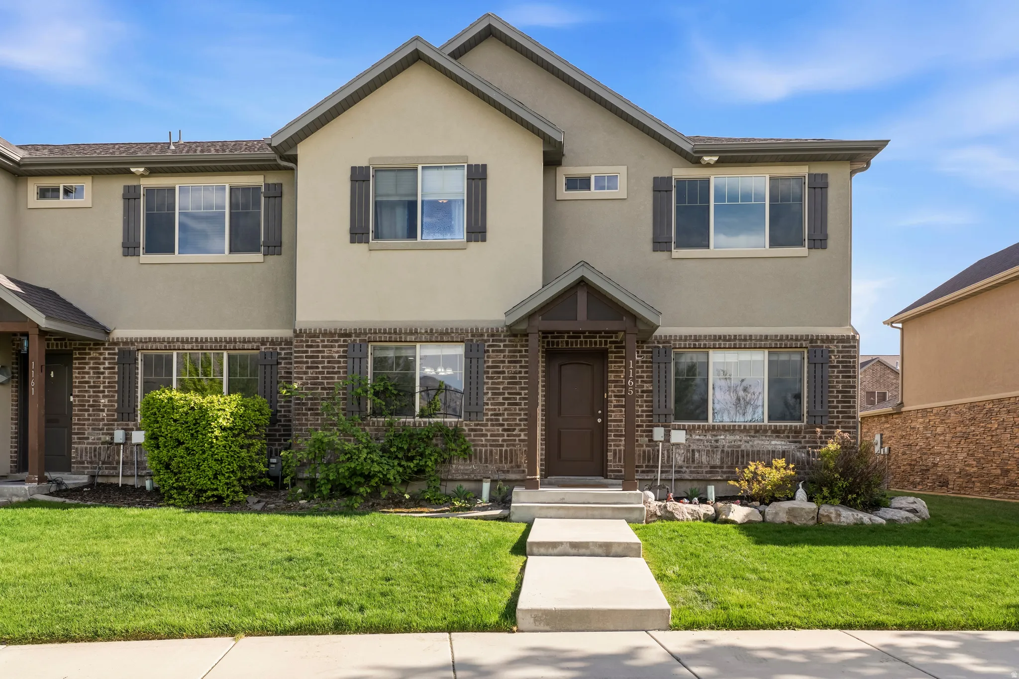 Traditional-style home with brick siding, stucco siding, and a front lawn