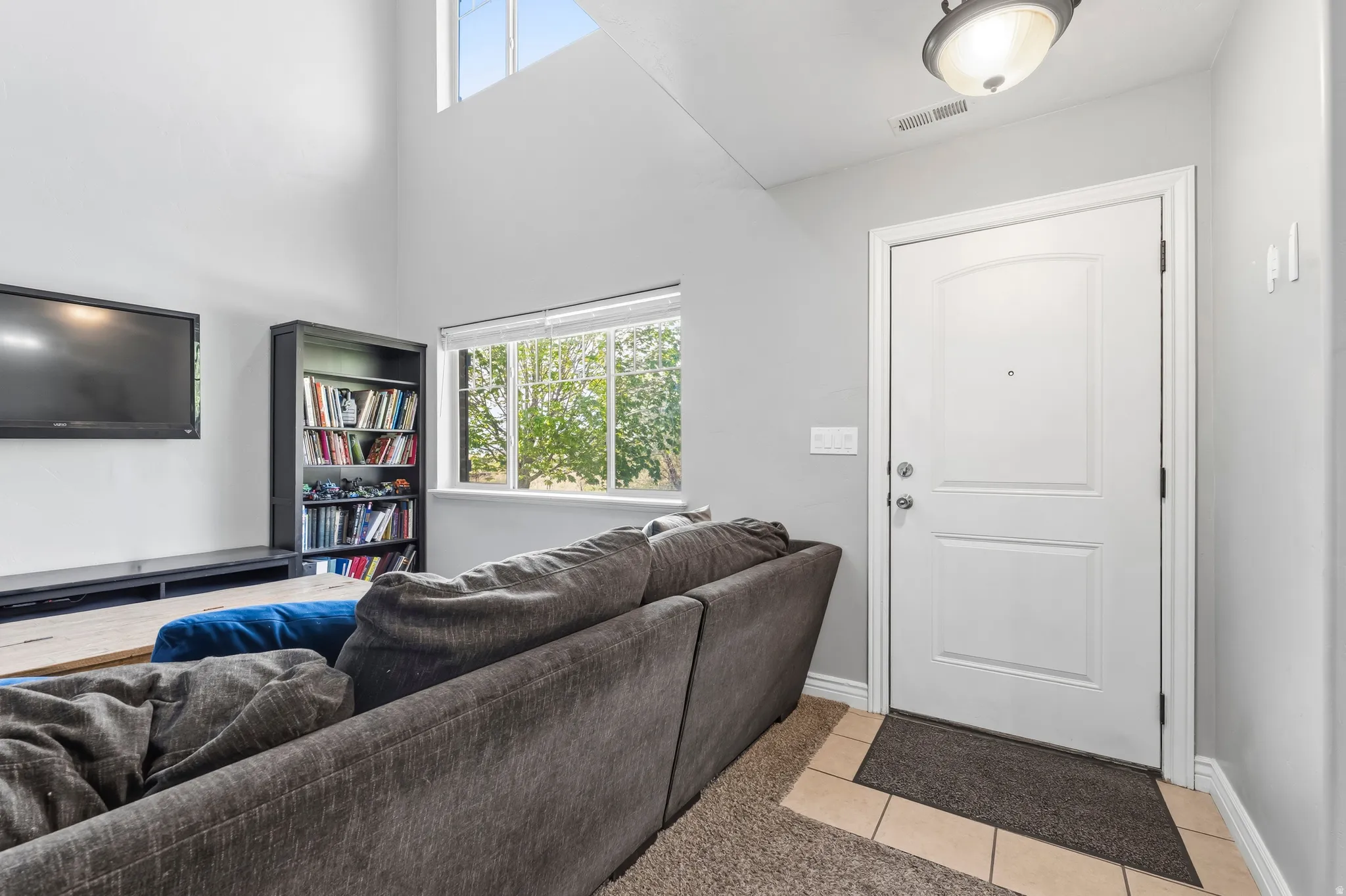Living room featuring plenty of natural light, light tile patterned flooring, and a high ceiling